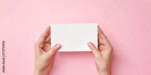 Woman's hands with manicure resenting folded blank paper sheet or booklet, against pastel pink background, Focus on crispness of paper and clean. Mock up adv advertisement concept