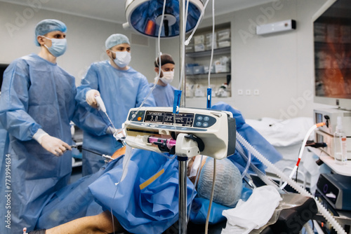A group of medical surgeons in the operating room during an operation. A patient on the operating table during laparoscopic abdominal surgery. The concept of modern medical equipment.