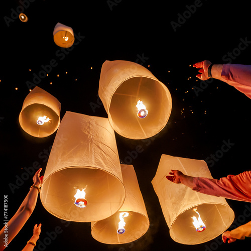 Family hands release hot air paper lanterns to sky at night in Loy krathong and Yi Peng Festival