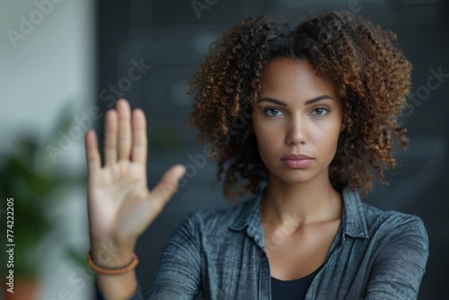 A serious-looking woman with a determined expression making a 'stop' gesture with her hand