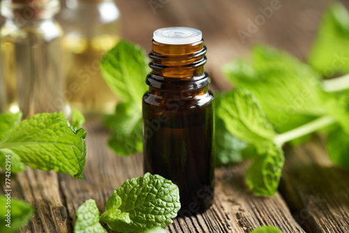 A brown glass bottle of essential oil with mint plant