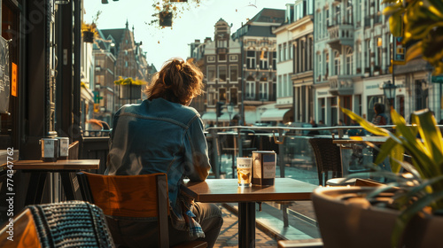 A man sits on the terrace of a café in the warm afternoon sun, watching the city go by