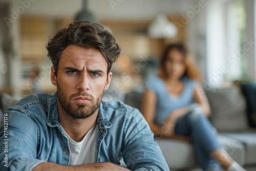 Upset young man sitting on the sofa and a woman in background ignoring each other at home. Stressed married couple sitting separately in the living room. Quarrel and divorce, Generative AI