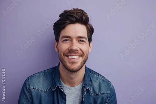 Portrait of a handsome young man smiling and looking at camera against purple background