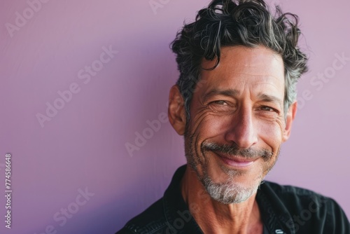Portrait of a handsome middle-aged man smiling at the camera against a purple background