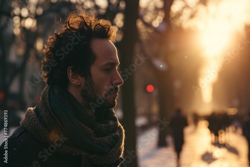 Portrait of a young handsome man with long curly hair and beard on the street at sunset