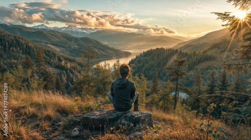 Man sitting on top of a mountain and enjoying the view of the lake.