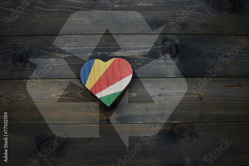 wooden heart with national flag of seychelles near reduce, reuse and recycle sing on the wooden background. concept