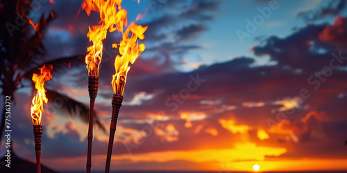 Hawaii luau party Maui fire tiki torches with open flames burning at sunset sky clouds at night