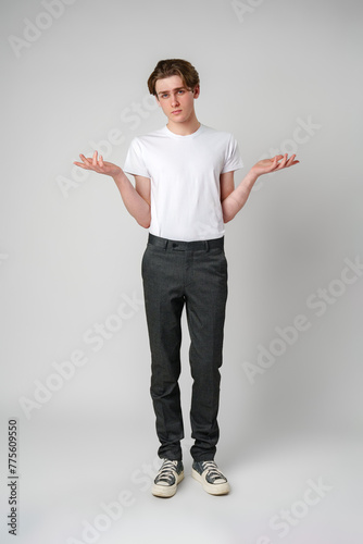 Young Man in White T-Shirt Displaying Uncertain Gesture Against Light Background