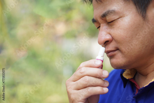 Asian man use menthol inhaler to smell for relief symptom of dizzy from hot weather condition. Concept, self first aid to protect from heat stroke. Refreshing. Aroma therapy. 