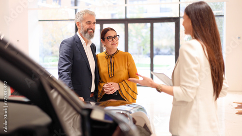 Young saleswoman recommending a car to a mature couple