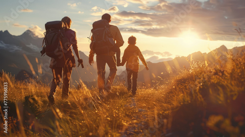 Back view of a family on a hike, walking through a sunlit field towards a mountain at sunset
