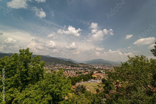Italian Bergamo city nestled upon a system of hills captured under a bright sky with fluffy clouds