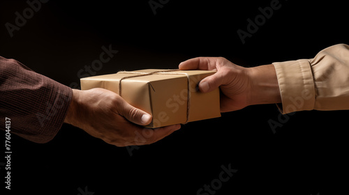 A mans hand passing a brown cardboard box to another persons hand on a black background