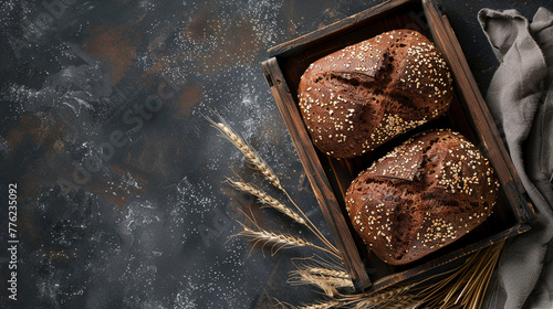 Two sourdough bread on a wooden tray with wheat and towel on dark background. Handmake bakery bread recipe concept. Flat lay, panoramic top view. copy space.