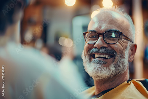 A man with glasses is smiling and sitting in a barber chair