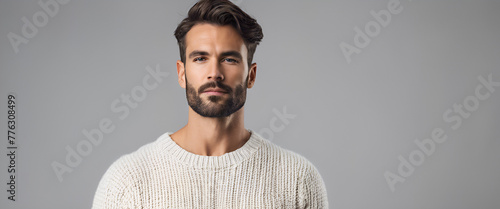 Photo of an attractive man wearing a white sweater against a solid grey background. Generative AI