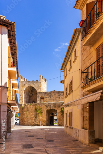 Street in Alcudia old town leading to the stone gate Porta del moll in Mallorca, Spain, Balearic Islands