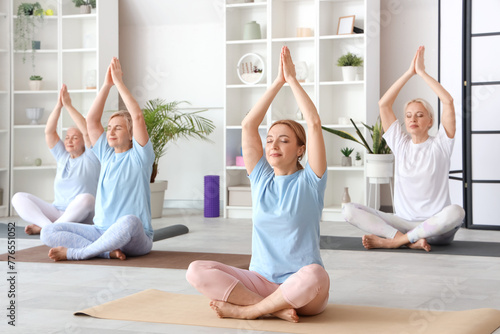 Group of mature women practicing yoga in gym
