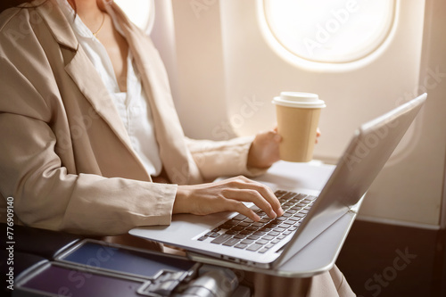 A cropped image of a hard-working businesswoman is working on her laptop during the flight.