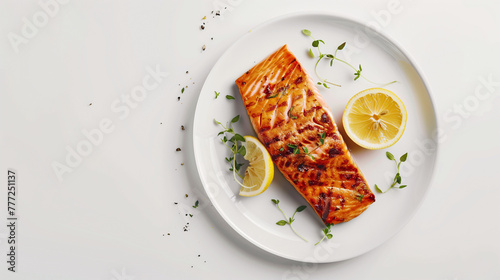 Grilled salmon fillets on a white plate with lemon slices and herbs. Studio photography with high contrast lighting. Healthy eating and seafood concept. Flat lay composition with copy space.