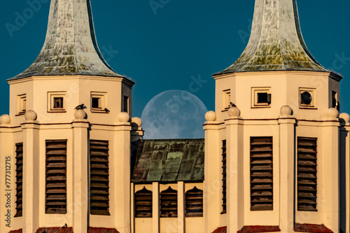 księżyc w pełni zachodzący za dwoma wieżami kościoła