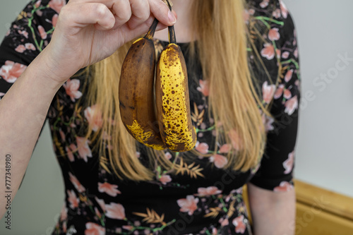 Kobieta trzyma marne, małe, brzydkie banany w dłoni 