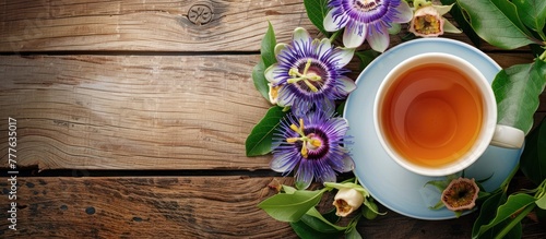 A cup of tea placed on a wooden table, flanked by colorful passiflora flowers.