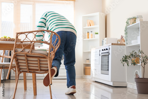 Man tripping over chair in kitchen