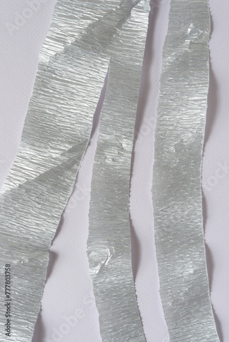 silver crepe paper streamer or stripes on blank paper with texture