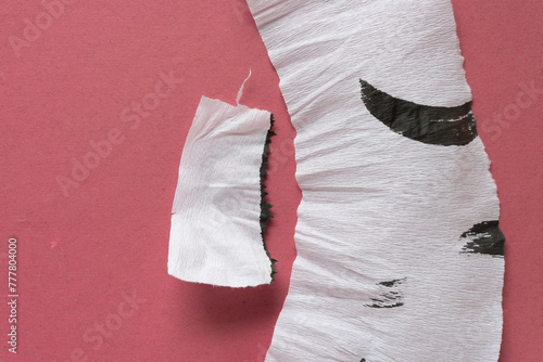 crinkled white crepe paper pieces with black ink stains on pink