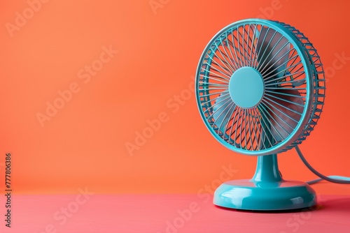 A blue fan sits on a red background. Summer heat concept