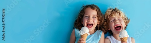 Two happy young children laughing and holding ice cream cones against a blue background.