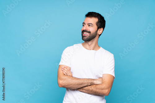 Young man with beard over isolated blue background happy and smiling