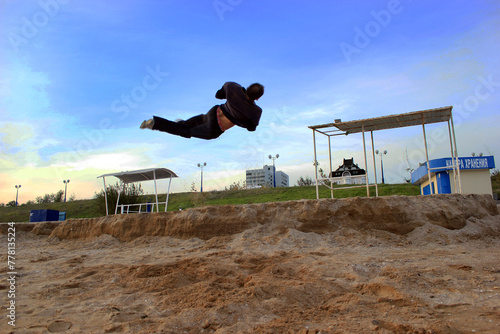 A young guy doing an acrobatic screw trick parallel to the ground against the sky from a small parapet 