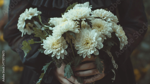 喪服を着て白い菊の花を手に持つ女性の手元のクローズアップ写真
