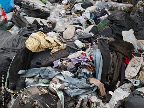 Close-up of pile of discarded clothes and other waste dumped at side of street in the West Midlands