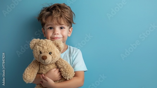 Little boy hugging stuffed toy on pastel blue background