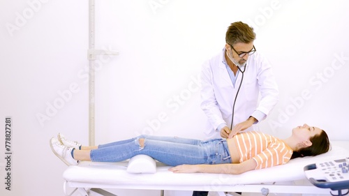 Doctor auscultating the patient's abdomen with a stethoscope