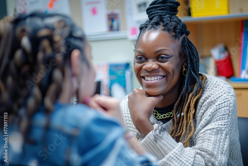 Smiling mental health professional looking at female student sitting with hand on chin in school office