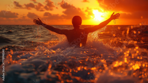 Silhouette of man splashing in the sea with tropical sunset