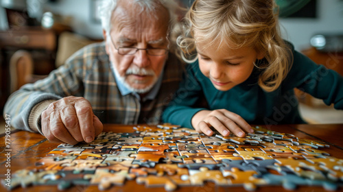 Little girl and her grandfather playing with jigsaw puzzle at home.