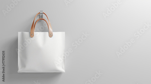 A white shopping bag with leather handles hangs against a textured beige wall.