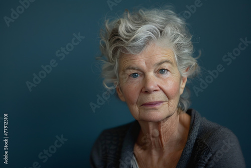 A woman with gray hair and blue eyes looks at the camera