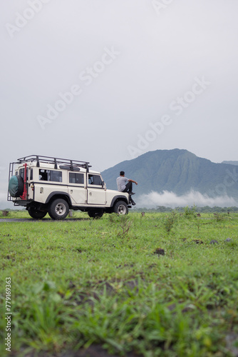 A man sits on a safari car and enjoys the beauty of Baluran National Park, Indonesia