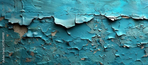 Close up view of peeling blue paint chipping off the surface of a weathered concrete wall, revealing the raw texture underneath