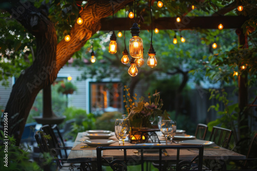 An antique chandelier hangs over an outdoor dining table, casting warm light on the backyard setting.