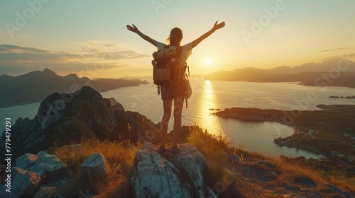 Woman with backpack standing on a mountain at sunset, arms raised in victory.