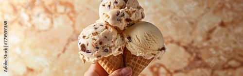 A hand firmly holds a scoop of ice cream in a waffle cone against a plain background